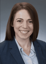 Jennifer Gasper, a dark haired woman wearing a blue jacket and light blue shirt.