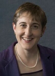 Carol Wayman, a brunette wearing a purple sport jacket and black shirt.