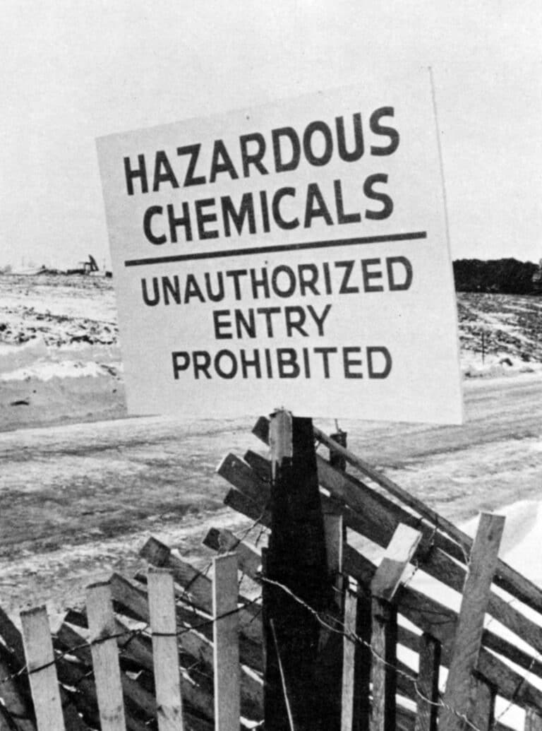 A warning sign with the text ‘Hazardous Chemicals’ posted by the fenced-in area of the Love Canal disaster site.